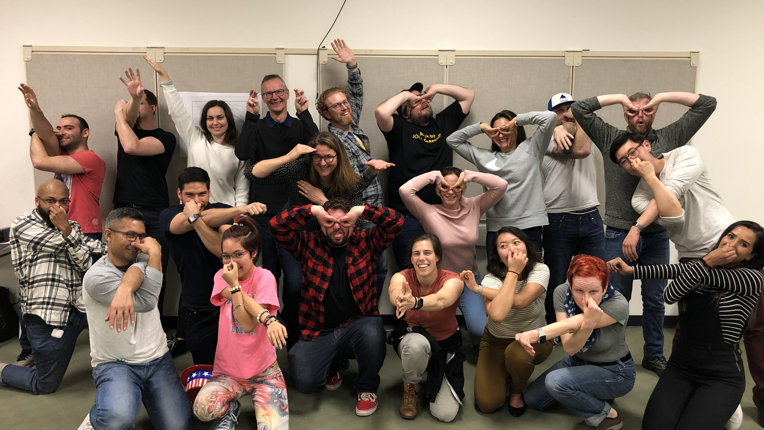 A corporate team laughing and making playful claws and horns during a Wit@Work improv workshop